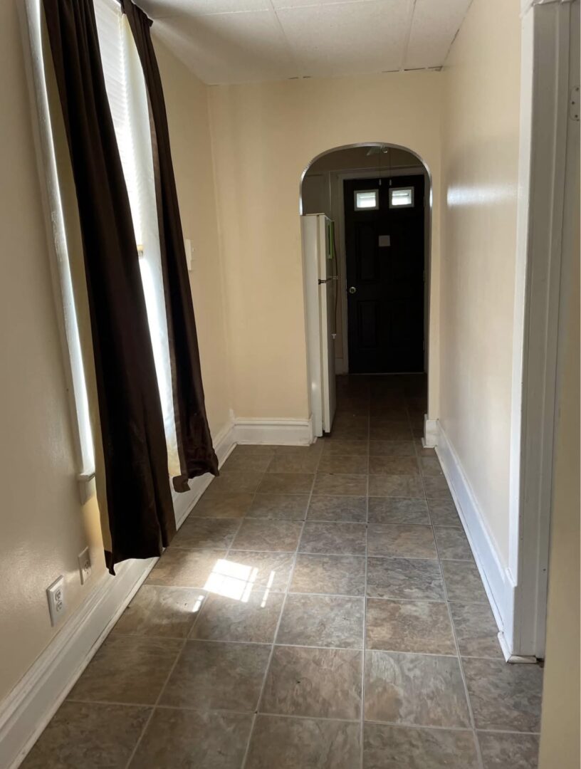 Narrow tiled hallway with arched doorway
