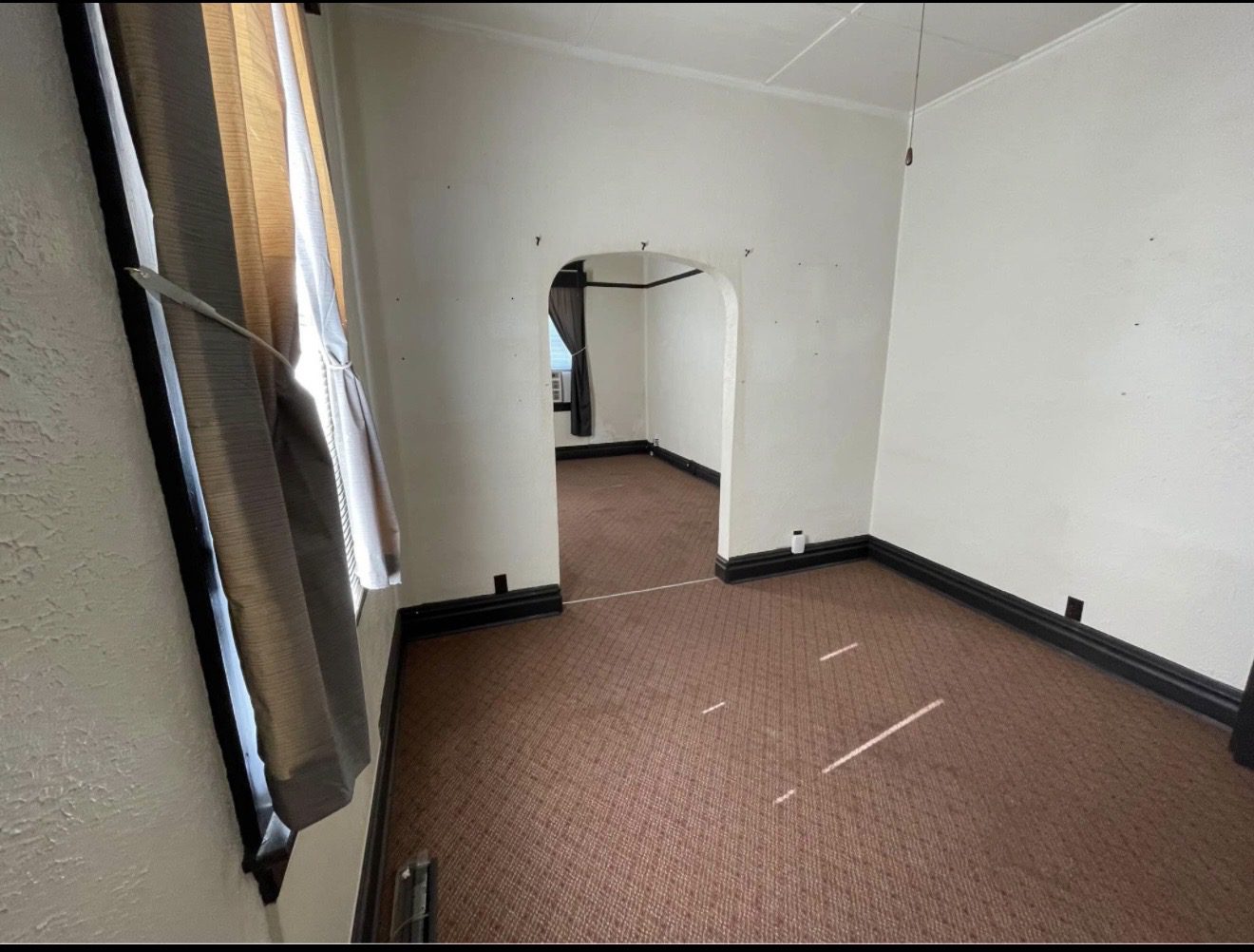 Archway connecting two carpeted rooms with curtain