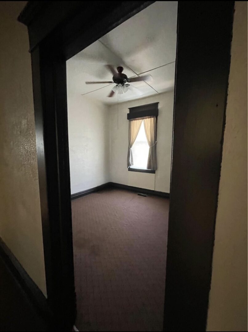 Doorway view into small bedroom with fan